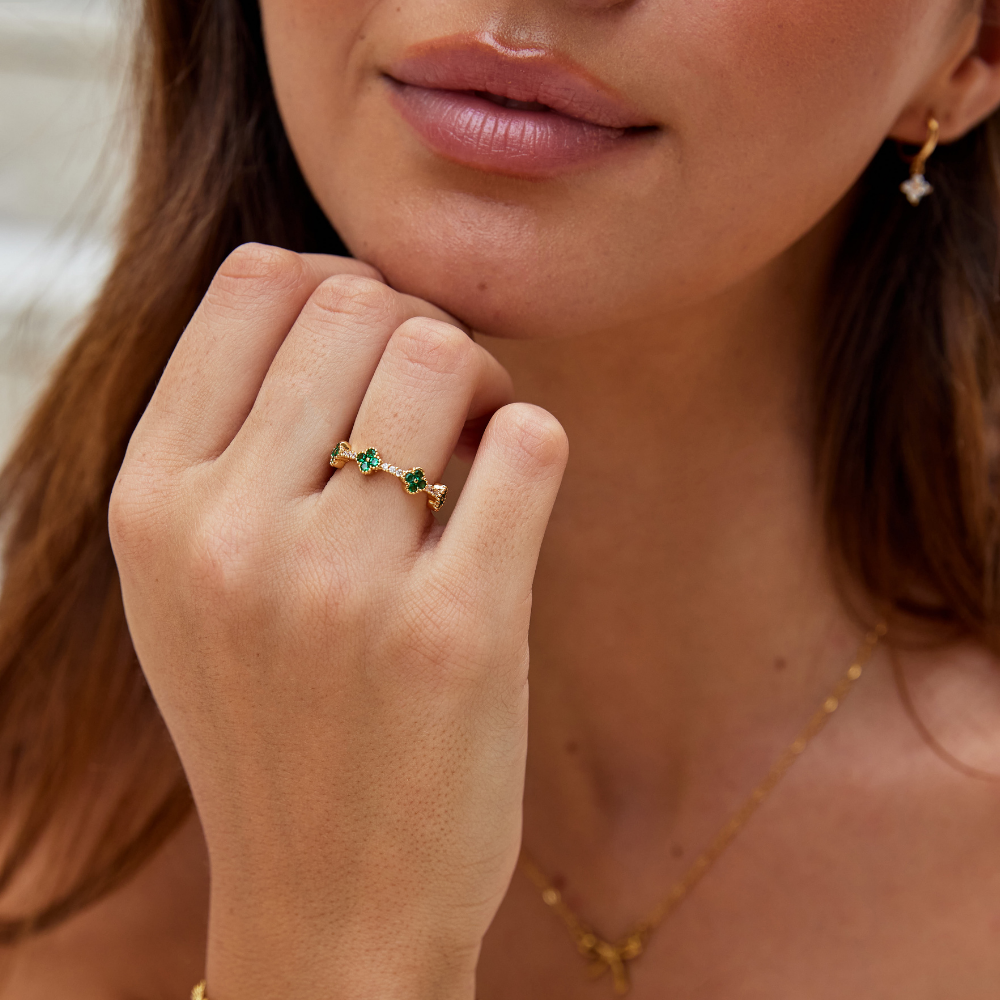 Annika – Guld ring med blomstrede detaljer og smaragdindslag.